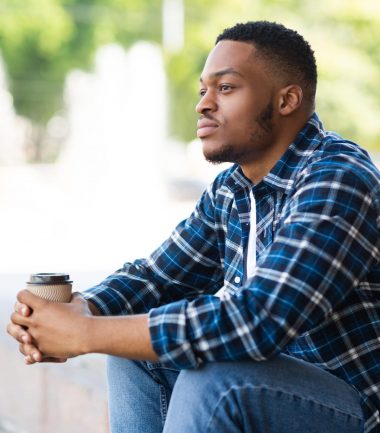 Portrait of pensive african american guy sitting with coffee